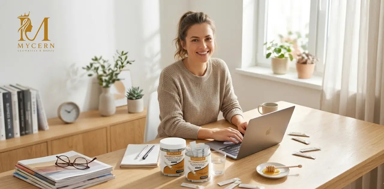 Woman working at her desk with MyCern Bee Bread Powder supplement jars and sachets beside her laptop, supporting daily energy and wellness